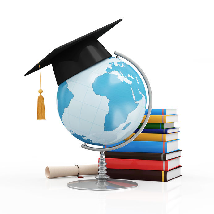 Black graduate cap on top of blue globe on white desk with variety of books and diploma nearby