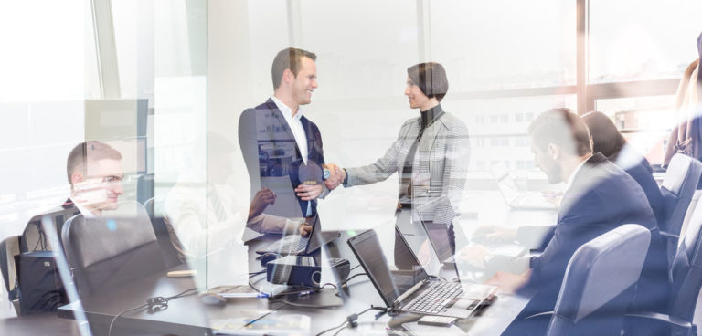 Business people shaking hands in modern corporate office.