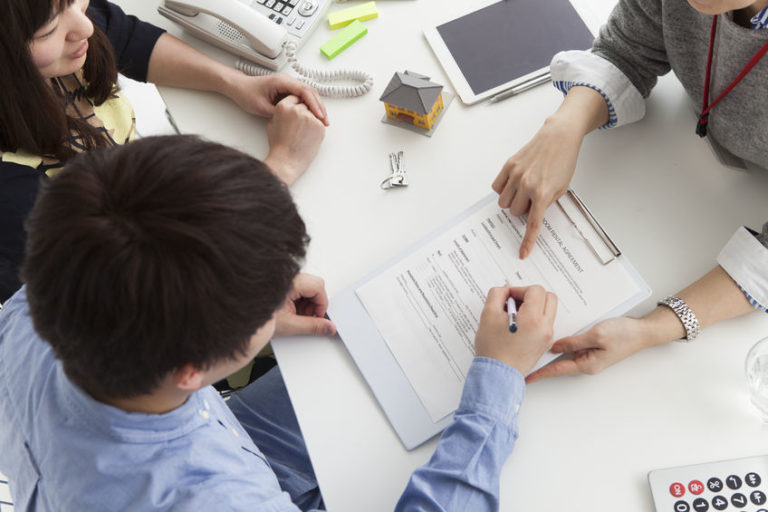 Young couple discussing Fiduciary Duties of Title Insurance Agents over white table with attorney