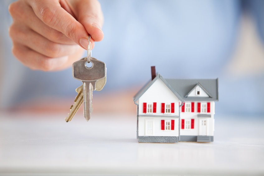 Woman holding keys next to a model house in an office in reference to caveat emptor