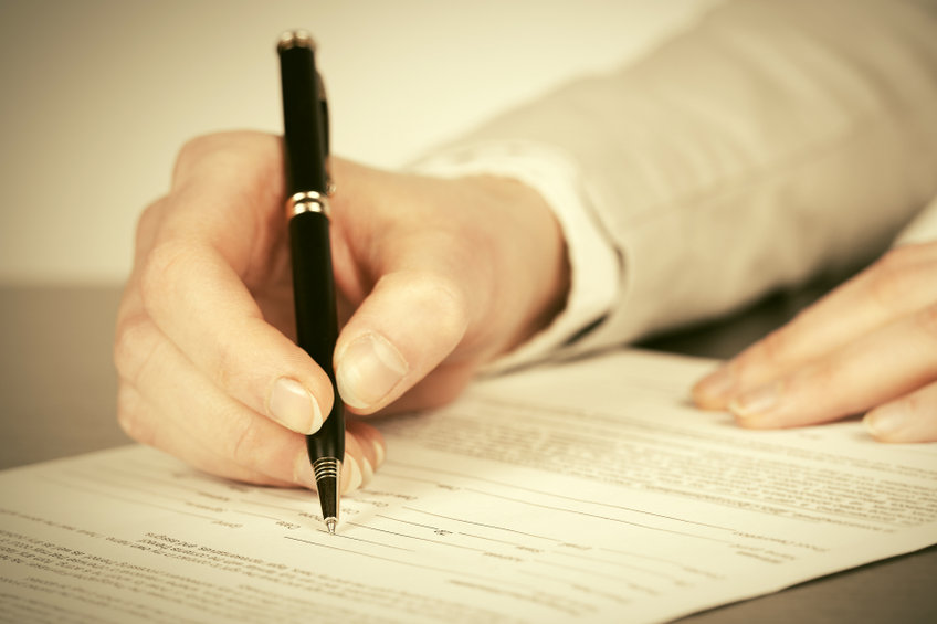Business woman signing contract in reference to disparagement clause