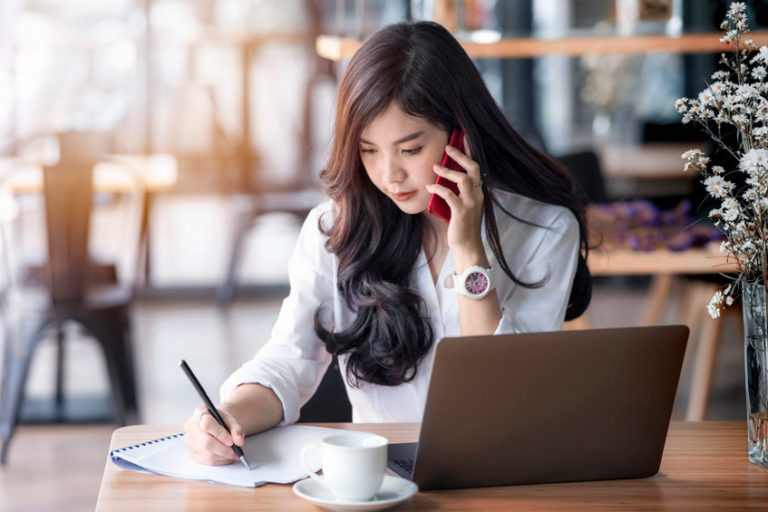 young asian business woman using laptop and writing on notebook in reference to exclusive distribution agreements