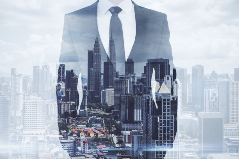 Businessman standing on creative Kuala Lumpur city background.