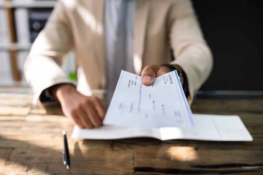 businessman handing employee a paycheck