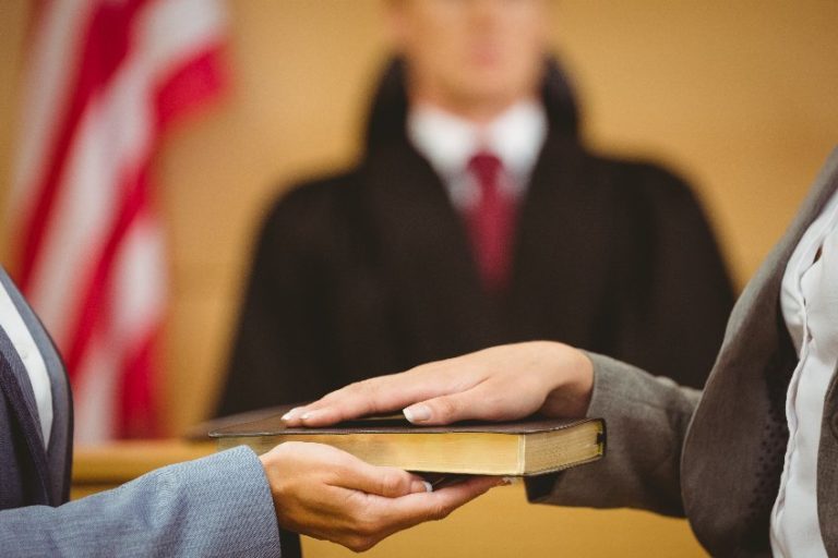 Picture of witness swearing on the bible telling the truth in the court room