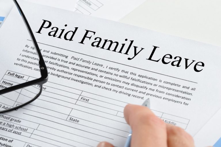 Picture of Close-up Of A Person's Hand Holding Pen Over Paid Family Leave Form With Spectacles
